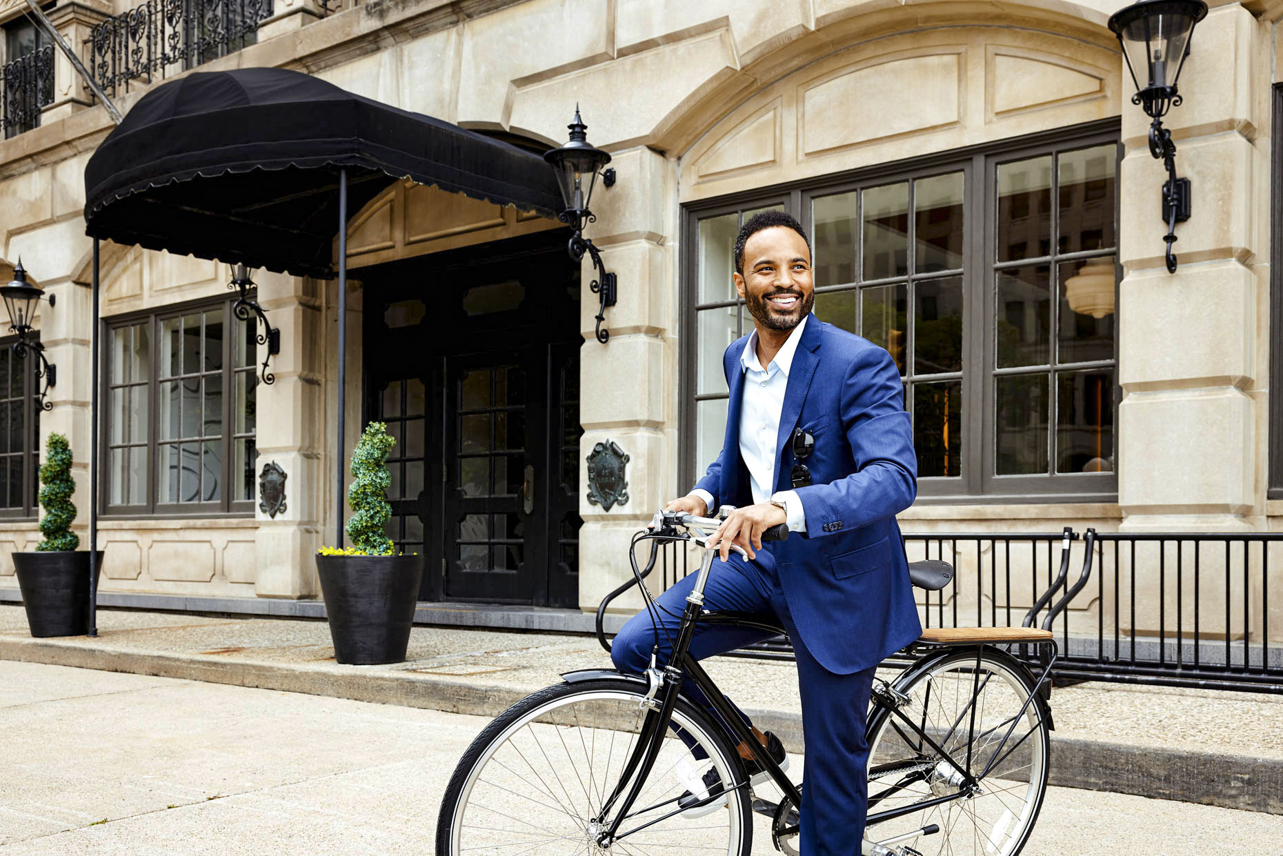 Portrait of stylish man smiling on bike in urban setting